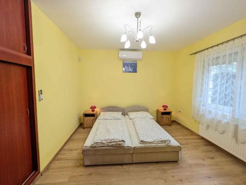 a bedroom with two beds in a room with yellow walls at Holiday home in Balatonlelle 53637 in Balatonlelle