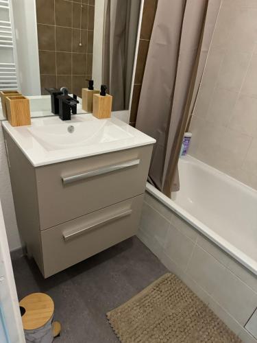 une salle de bain avec un lavabo blanc et une baignoire dans l'établissement Appartement, Cozy trois, à Toulouse