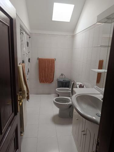 a white bathroom with a toilet and a sink at Casa do Outeirinho in Campos