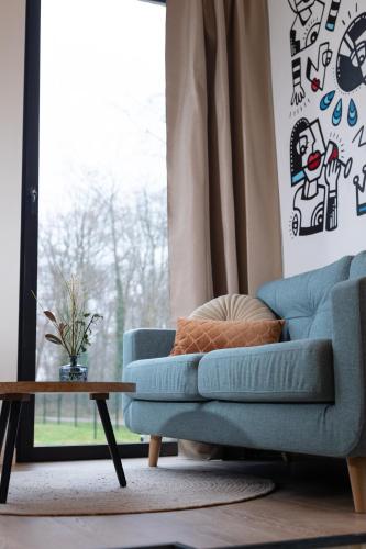 a living room with a blue couch and a table at Bed & Breakfast De Pol in Doetinchem