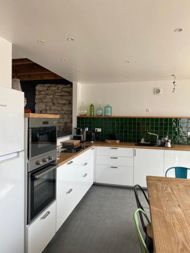 une cuisine avec des armoires blanches et une table en bois dans l'établissement Maison 14 personnes, à Plozévet