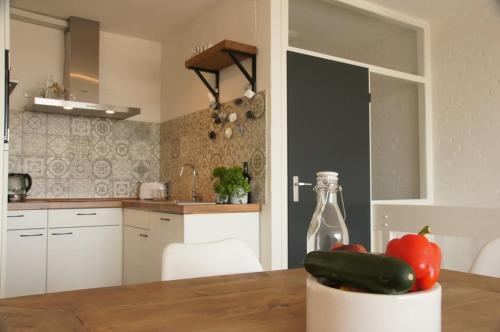 a kitchen with a table with a cucumber and a bottle at Vakantiewoning Bruinisse aan Jachthaven Zeeland, VP012 in Bruinisse