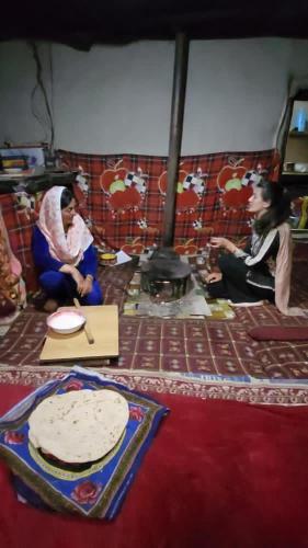 a group of people sitting on the floor with a cake at Pamir Serai in Dargai