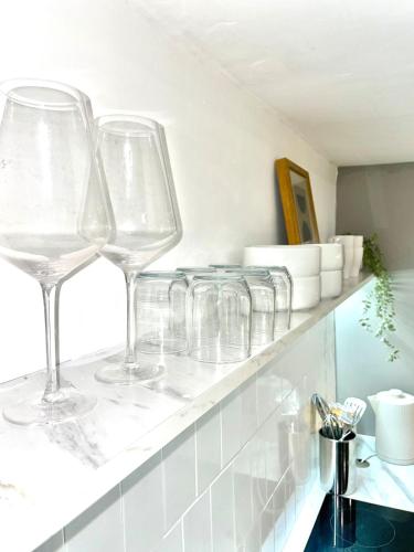 a row of wine glasses sitting on a shelf at A2 HighTown Apartment, Steps from Luton Train Station in Luton