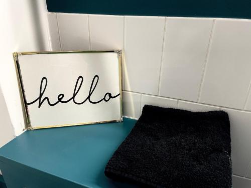 a sign with the word hello sitting on a blue counter at A2 HighTown Apartment, Steps from Luton Train Station in Luton