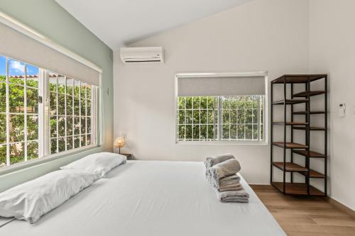 a white bedroom with a large bed and a book shelf at Kas di Rosa Curacao luxurious holiday home in Grote Berg