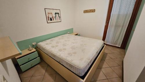 a small bedroom with a bed and a dresser at Villaggio Tirreno appartamento 02 in Rosolina Mare