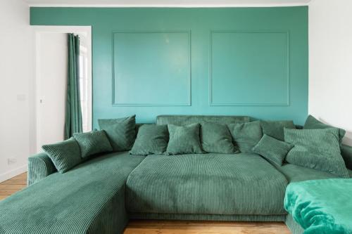 - un grand canapé vert dans une pièce aux murs bleus dans l'établissement Bright apartment near the City of Light, à Saint-Denis