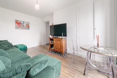 un salon avec un canapé vert et une télévision dans l'établissement Bright apartment near the City of Light, à Saint-Denis