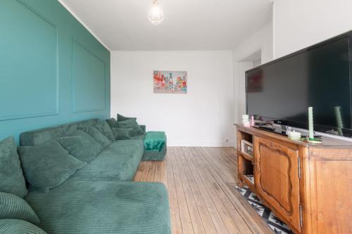 un salon avec un canapé vert et une télévision à écran plat dans l'établissement Bright apartment near the City of Light, à Saint-Denis