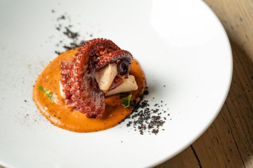 a white plate with a piece of meat and orange sauce at Elide Design Hotel in Assisi