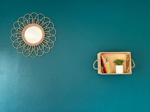 un miroir accroché à un mur bleu avec une étagère dans l'établissement TORINO - Appartement cozy, à Sarrebourg
