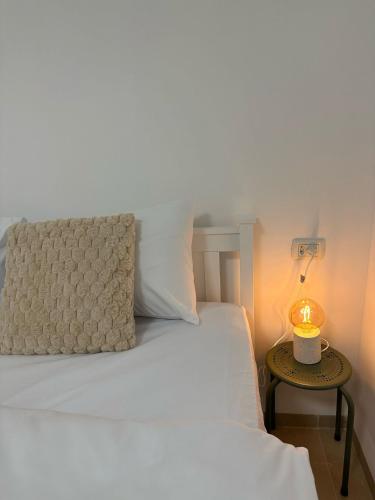 a bedroom with a white bed with a lamp on a table at Ocean view - מול הים in Nahariyya