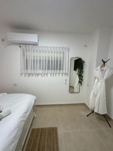 a white bedroom with a bed and a mirror at Ocean view - מול הים in Nahariyya