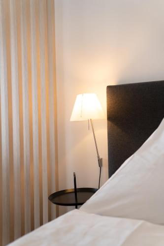 a room with a bed and a table with a lamp at Das Loft Apartments in Aachen