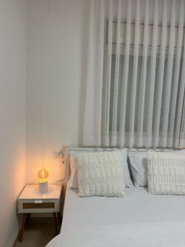 a bed with two pillows and a table with a lamp at Ocean view - מול הים in Nahariyya