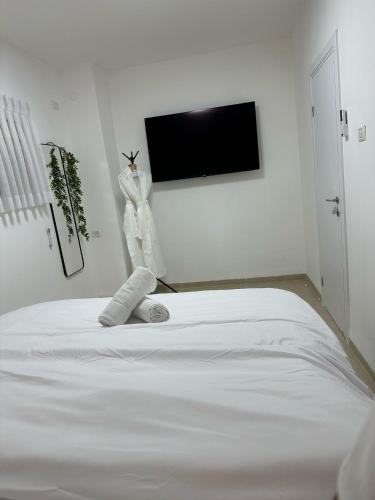 a white bedroom with a bed and a flat screen tv at Ocean view - מול הים in Nahariyya