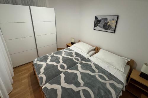 a bedroom with a bed with a gray and white blanket at Apartment Pirun in Baška