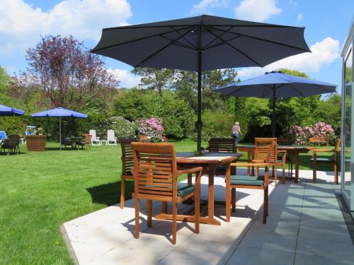 a group of tables and chairs with an umbrella at Hotel zum Rosenteich in Bad Zwischenahn