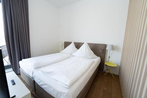 a bedroom with a bed with white sheets and a window at Das Loft Apartments in Aachen