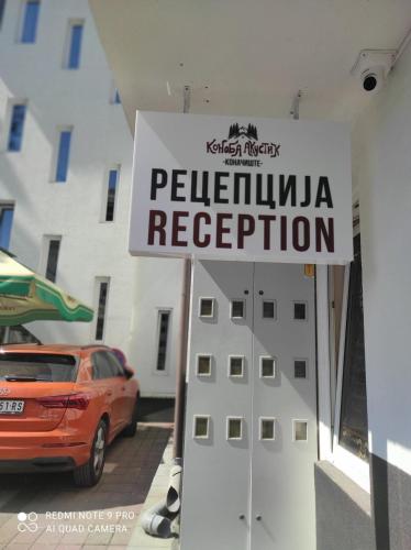 a sign in a parking lot with a car and a building at Hotel Konačište Akustik in Zlatibor