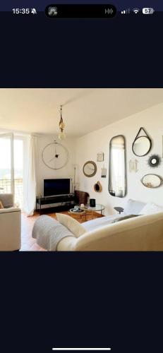 - un salon avec un grand canapé et une horloge murale dans l'établissement Charmante maison de village haut de cagnes, à Cagnes-sur-Mer