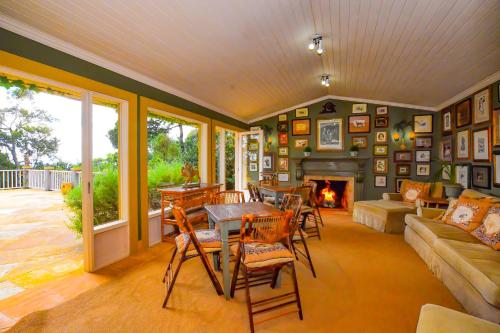 a living room with a table and chairs and a fireplace at Villa Coração Guesthouse by Concavus in Monte Verde