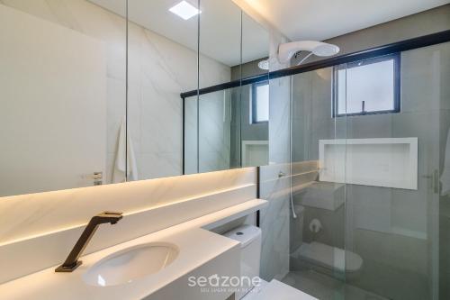 a bathroom with a sink and a glass shower at Apartamentos no Edifício Turquesa - Balneário Piçarras - RTS in Piçarras
