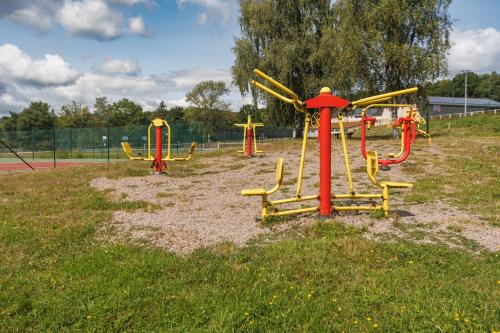 un parc avec une aire de jeux dotée d'équipements jaunes et rouges dans l'établissement Les Demeures du Lac, à Saint-Rémy-sur-Durolle