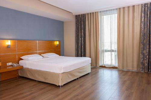 ein Schlafzimmer mit einem großen Bett und einem großen Fenster in der Unterkunft Anemon Kent Çiğli Otel in Izmir