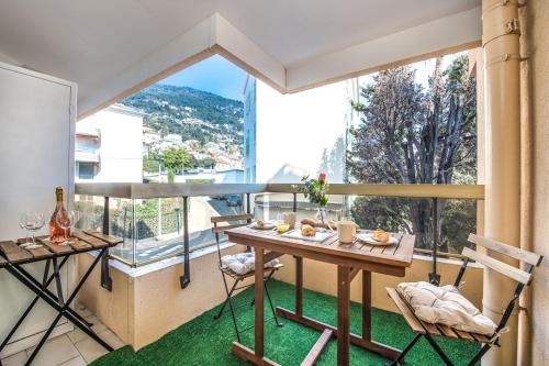 un balcon avec une table et des chaises et une grande fenêtre dans l'établissement Beaurivage, à Menton