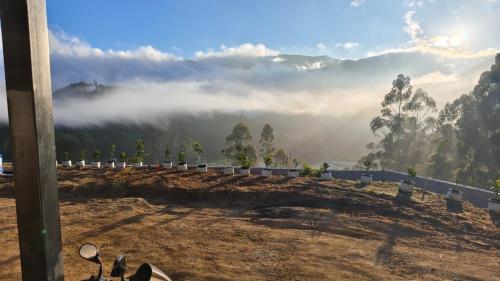 a view of a hill with fog in the mountains at Orange Valley Farm Resort in Munnar