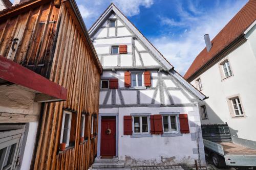 a white house with red doors next to two buildings at RefuKium alte Kutscherei in Weißenburg in Bayern