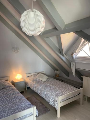 a bedroom with two beds and a chandelier at Au Petit Bonheur in Thannenkirch
