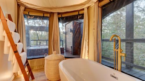 a bathroom with a tub and a large window at The Covery the Wren House a luxury African tent retreat on stocked bass pond in Hot Springs