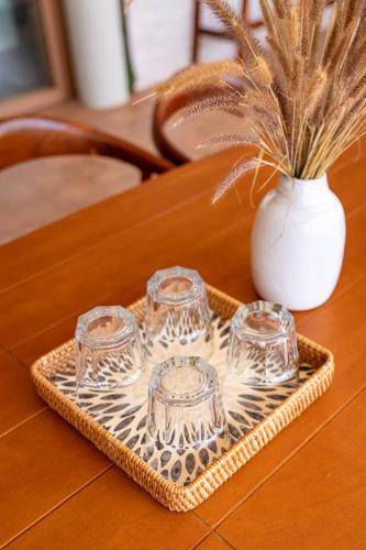 a tray with four glasses and a vase on a table at Amaya Kampot Homestays in Kampot