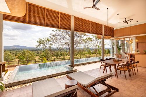 an open living room with a pool and a table and chairs at Amaya Kampot Homestays in Kampot