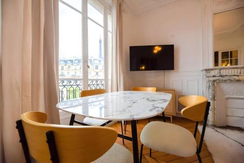 une salle à manger avec une table et des chaises et une fenêtre dans l'établissement TBS 323 - Superb apartment with Eiffel Tower view, à Paris