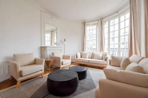 un salon avec des meubles blancs et une grande fenêtre dans l'établissement TBS 323 - Superb apartment with Eiffel Tower view, à Paris
