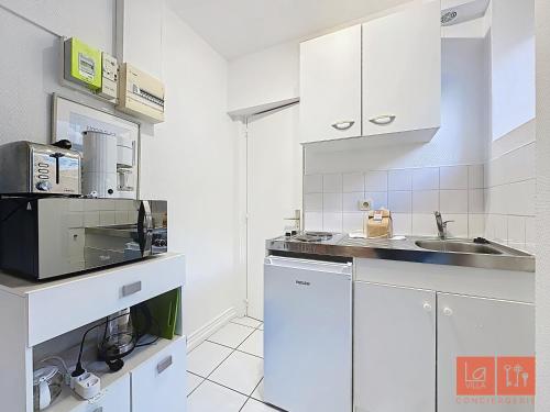 une cuisine blanche avec un évier et un micro-ondes dans l'établissement Joli Studio proche plage et centre avec parking, à Wimereux