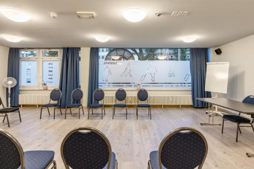 a room with chairs and a table and a projection of people at a&o Düsseldorf Hauptbahnhof in Düsseldorf