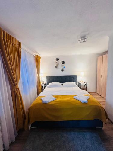 a bedroom with a large bed with yellow sheets at Casa Ana in Călimăneşti