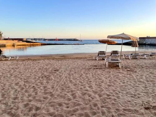 two chairs and an umbrella on a beach at Neues Studio direkt am Strand in Arguineguín