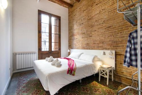 Un dormitorio con una cama blanca y una pared de ladrillo. en Happy People Plaza España Apartments, en Barcelona