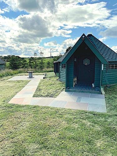 a small blue building in the middle of a field at Holly Tree Glamping Cabins in Wigglesworth