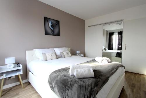 une chambre avec un grand lit blanc et un miroir dans l'établissement TERA2 - Charme de Disneyland Paris Vallée Village, à Serris