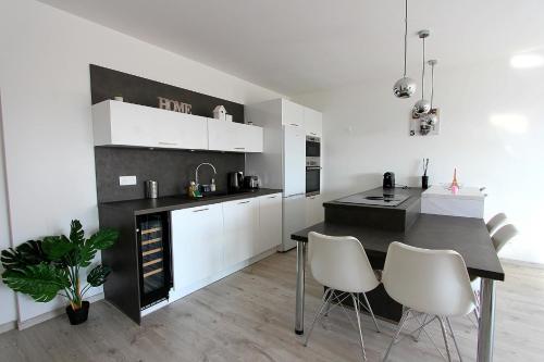 une cuisine avec un comptoir noir et des armoires blanches dans l'établissement TERA2 - Charme de Disneyland Paris Vallée Village, à Serris