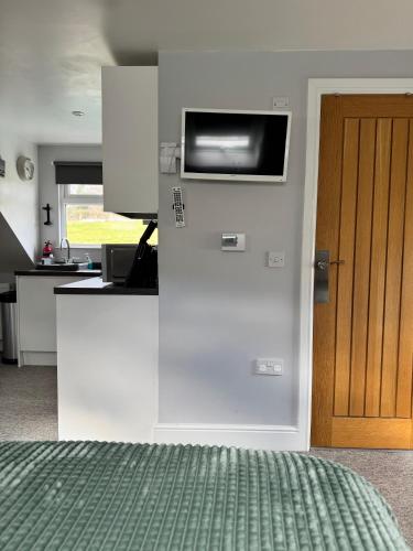 a kitchen with a refrigerator with a television on the wall at The Annexe rural retreat near Bath in Bath