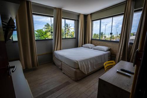 a small room with a bed and two windows at Bessa Golden Flats in João Pessoa