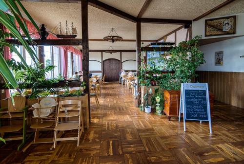 a restaurant with tables and chairs and plants and a chalkboard at Elbterrassen zu Brambach in Dessau